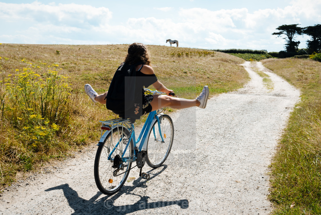 "Pretty young woman riding bicycle in a country road" stock image