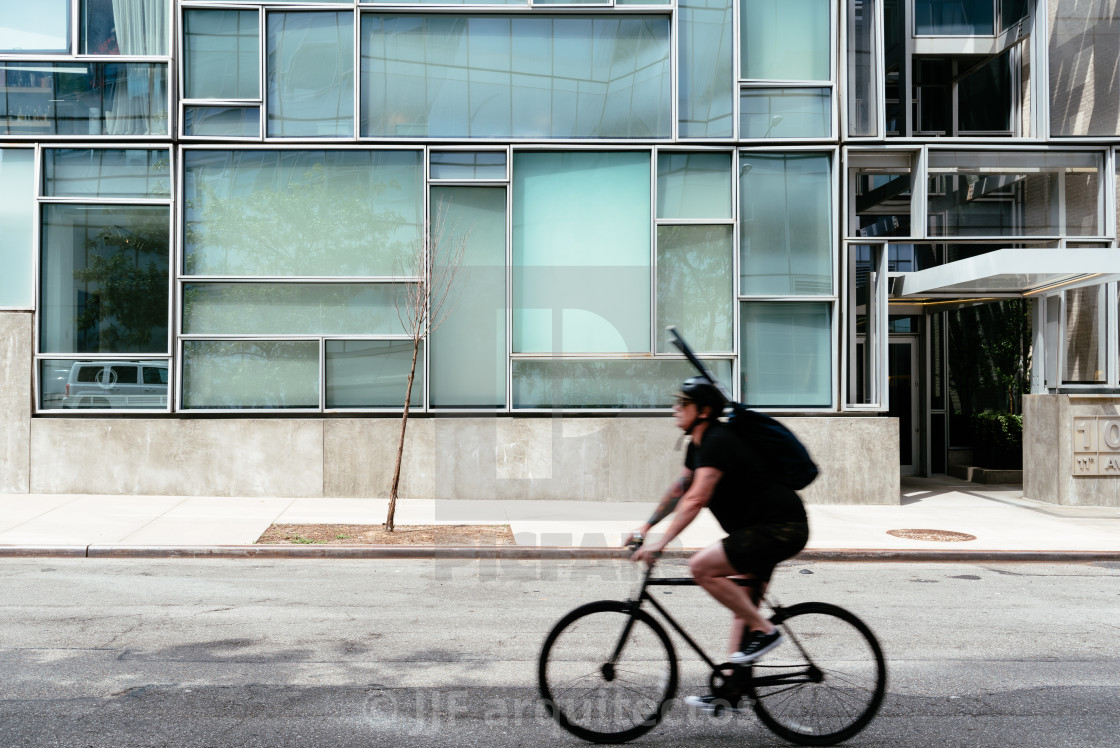 "Cyclist riding against minimalist style building NYC" stock image