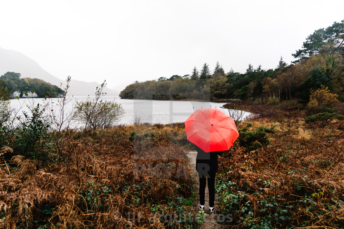 "Woman with red umbrella by lake in Ireland" stock image