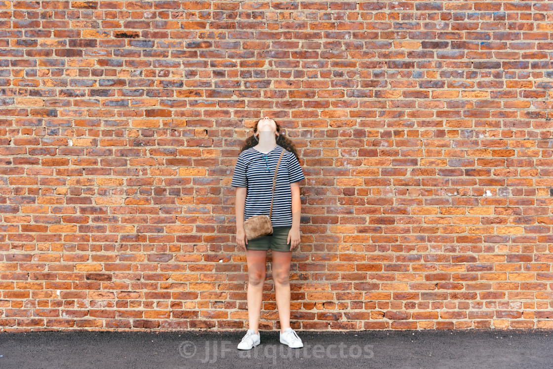 "Girl looking up against brick wall background" stock image