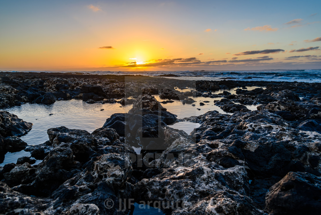 "Scenic view of rocky beach at sunset" stock image