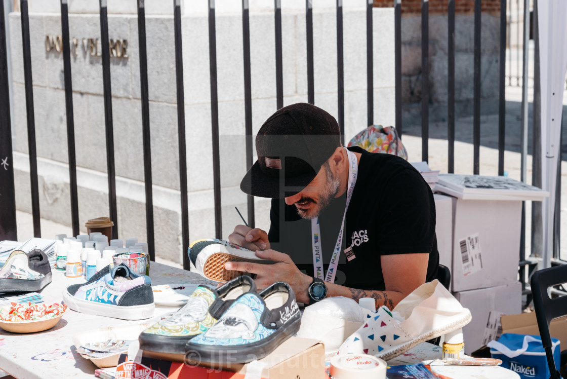 "Artist painting shoes in Malasana district in Madrid" stock image