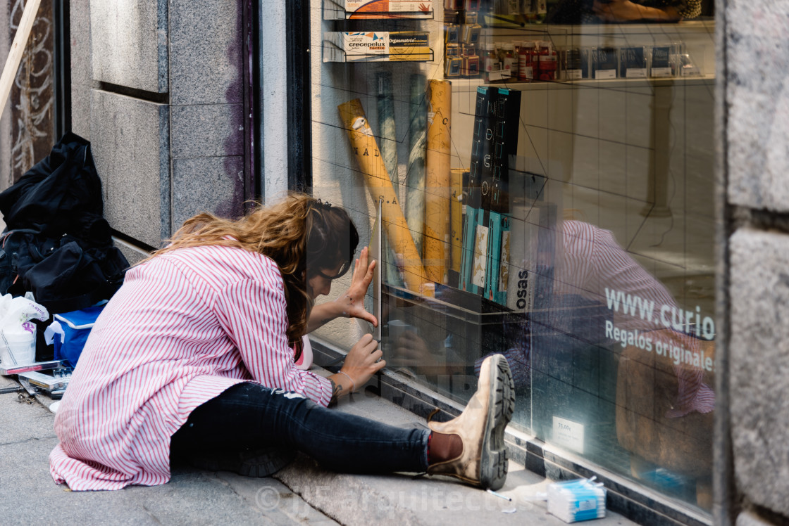 "Artist woman painting storefront in Malasana district in Madrid" stock image