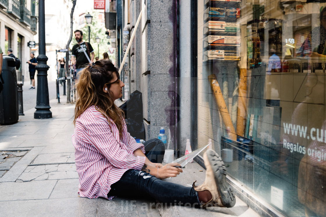 "Artist woman painting storefront in Malasana district in Madrid" stock image