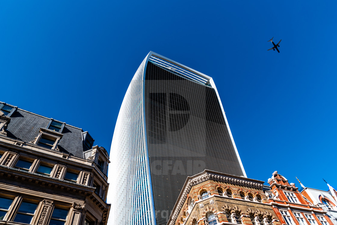 "Plane flying over skyscraper in London against sky" stock image