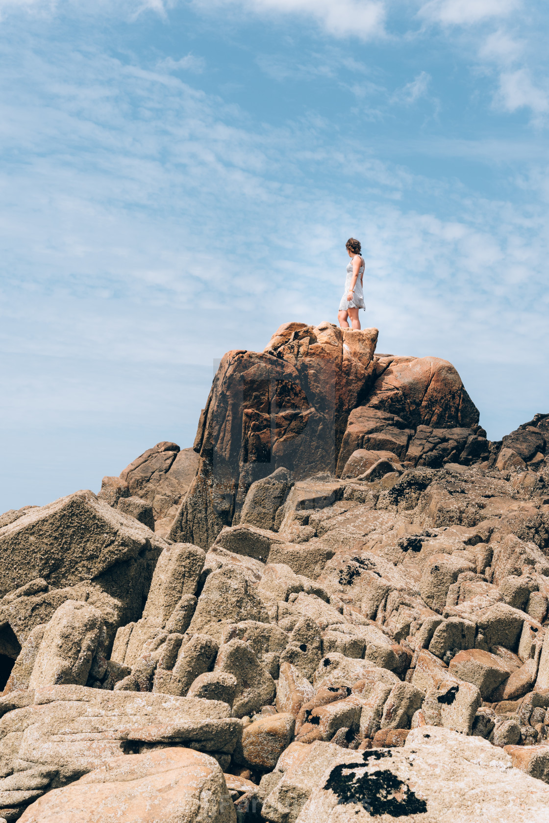 "Young woman on top of rocks against sky" stock image