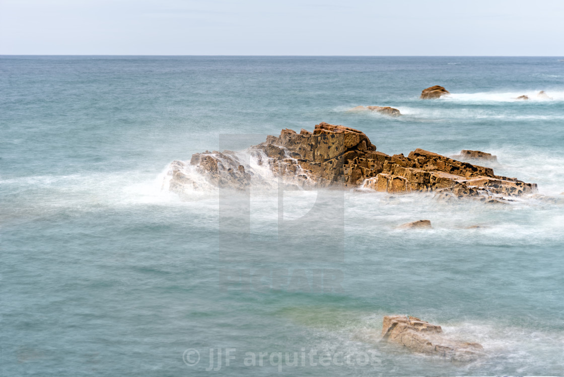 "Scenic view of waves splashing against rocks" stock image