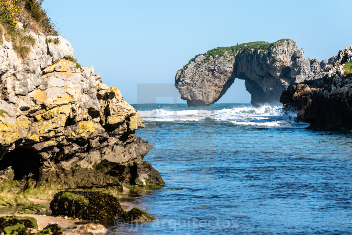 "Scenic view of sea against blue sky in rocky coast" stock image