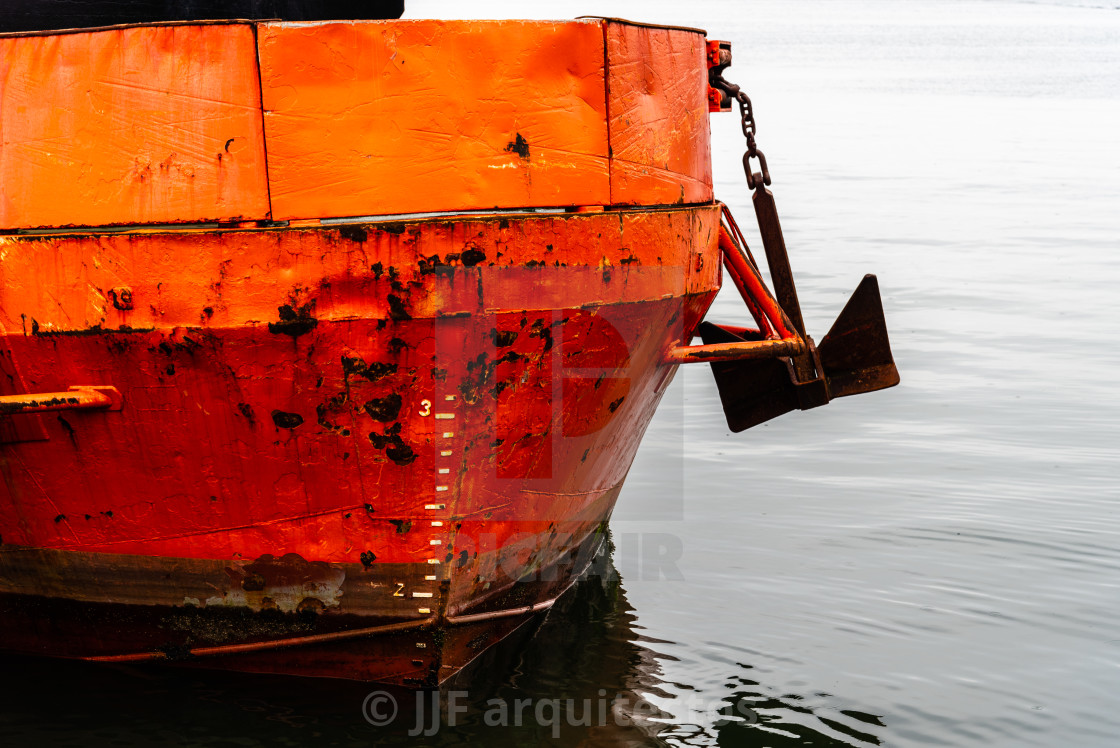 "Close-up of prow of old rusty red ship moored in harbour" stock image