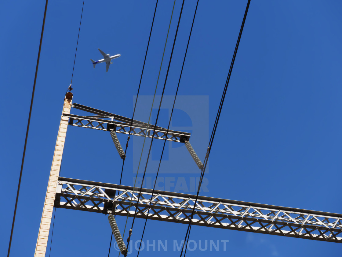 "Jet flying over the train station power lines" by JOHN MOUNT - $25.10 "Jet flying over the train station power lines" stock image
