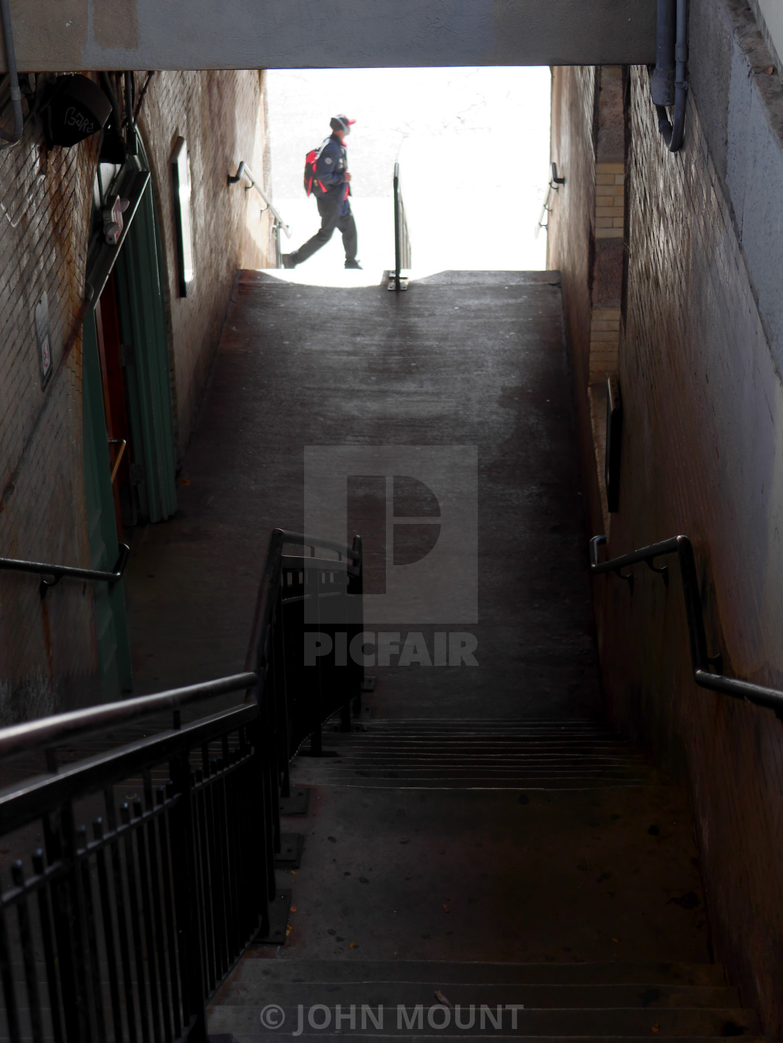 "Train station stairs with passing pedestrian" by JOHN MOUNT - $25.10 "Train station stairs with passing pedestrian" stock image
