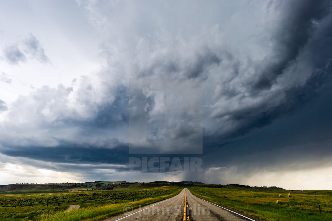 "Straight road leading to dark storm clouds" stock image