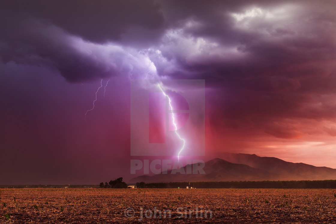 "Lightning bolt striking a mountain during a storm at sunset" stock image