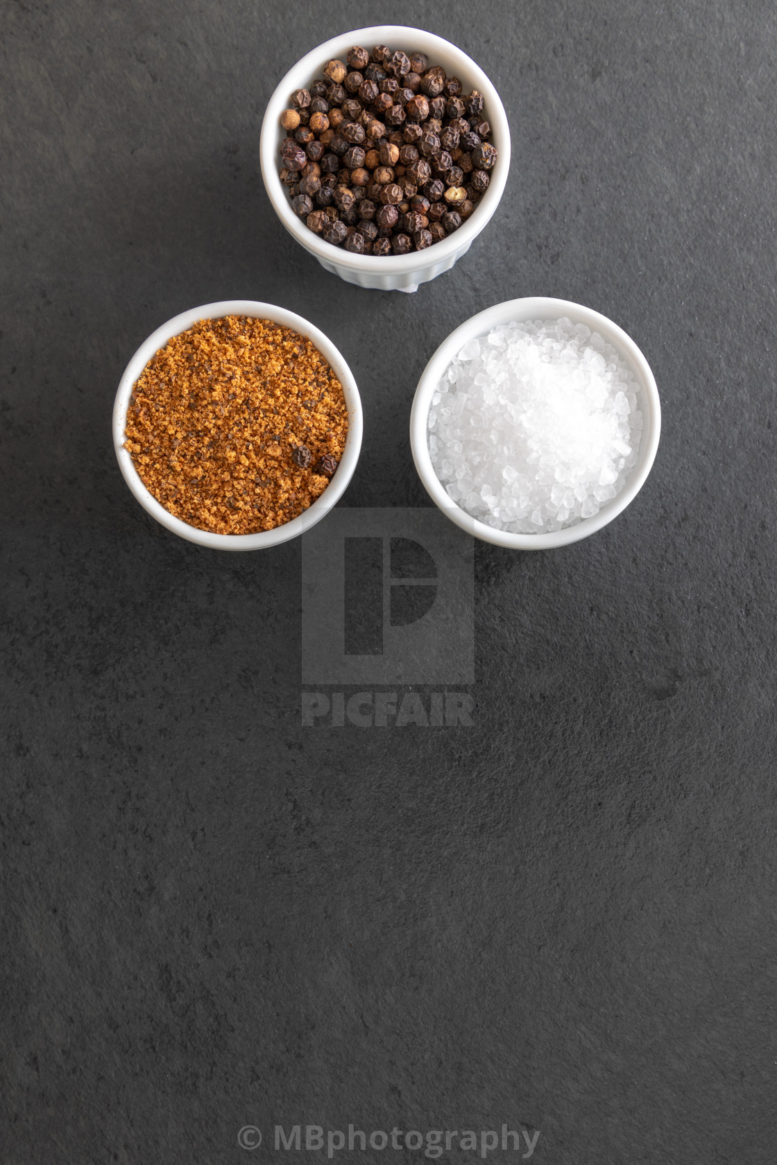 "Sea salt, pepper grains and bbq rub on dark stone surface, close" stock image