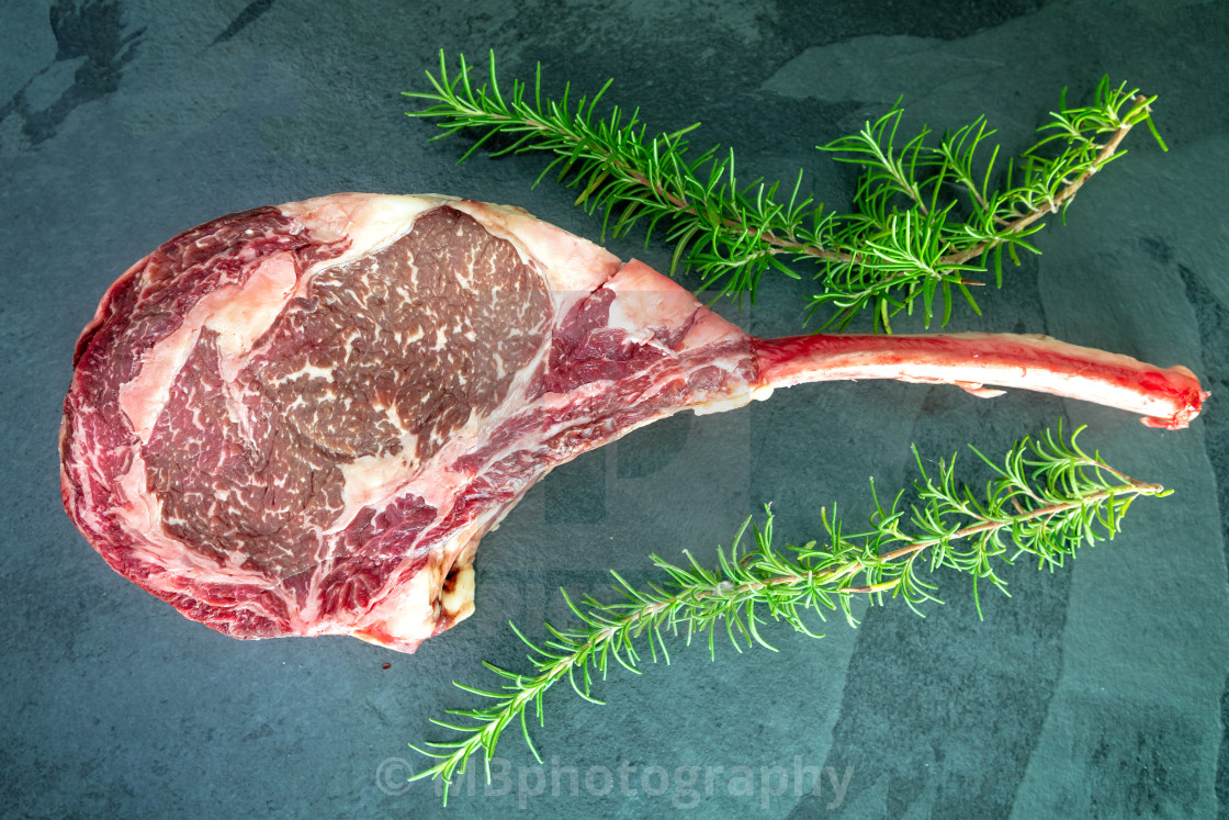 "Raw ,dry-aged wagyu tomahawk steak and rosemary on a black ston" stock image