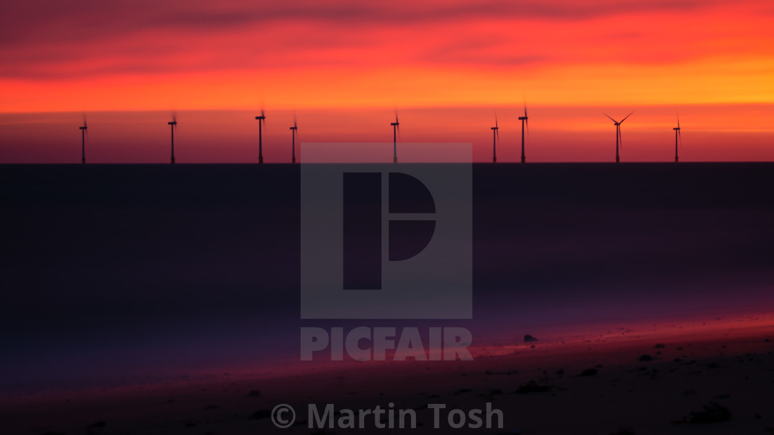 "Electric. Orange dawn with wind farm and beach" stock image