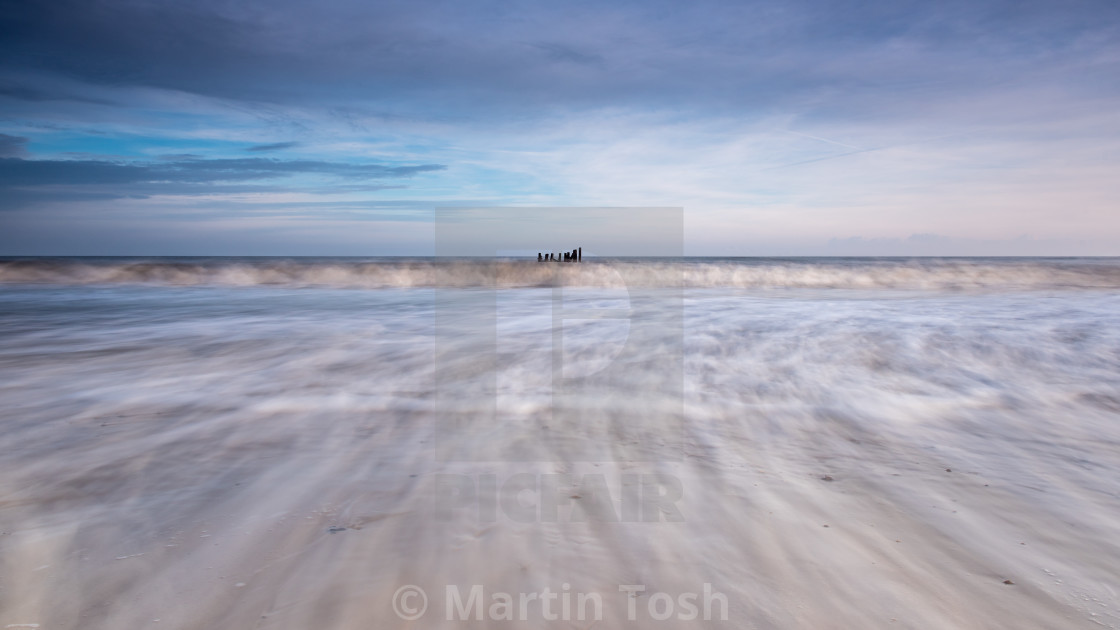 "Swooshing surf and old sea defences" stock image