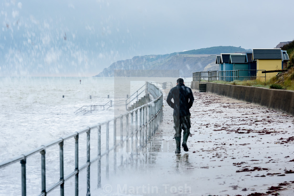 "Drookit. Stormy seas and beach huts with walking figure" stock image