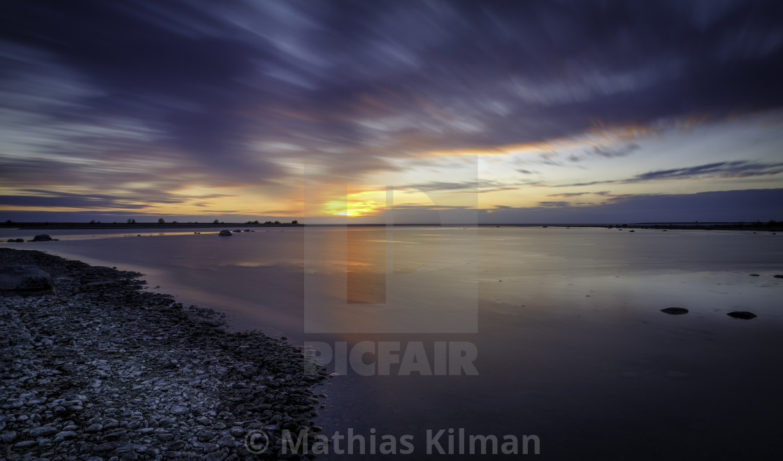 Long Exposure Of Sunset At The Sea With A Rocky Beach As