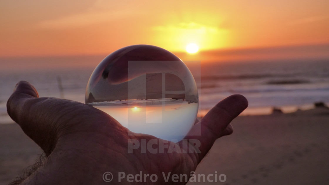 "holding a crystal ball at sunset on the beach" stock image