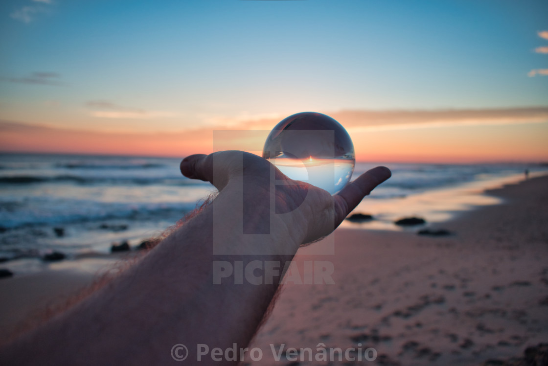 "Cristal ball on hand at sunset on the beach" stock image