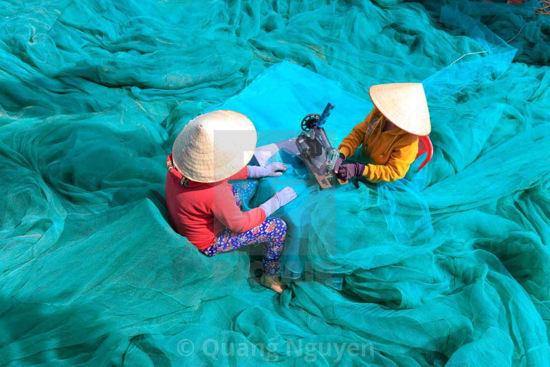 "two women are sewing fishing nets in fishing village" stock image