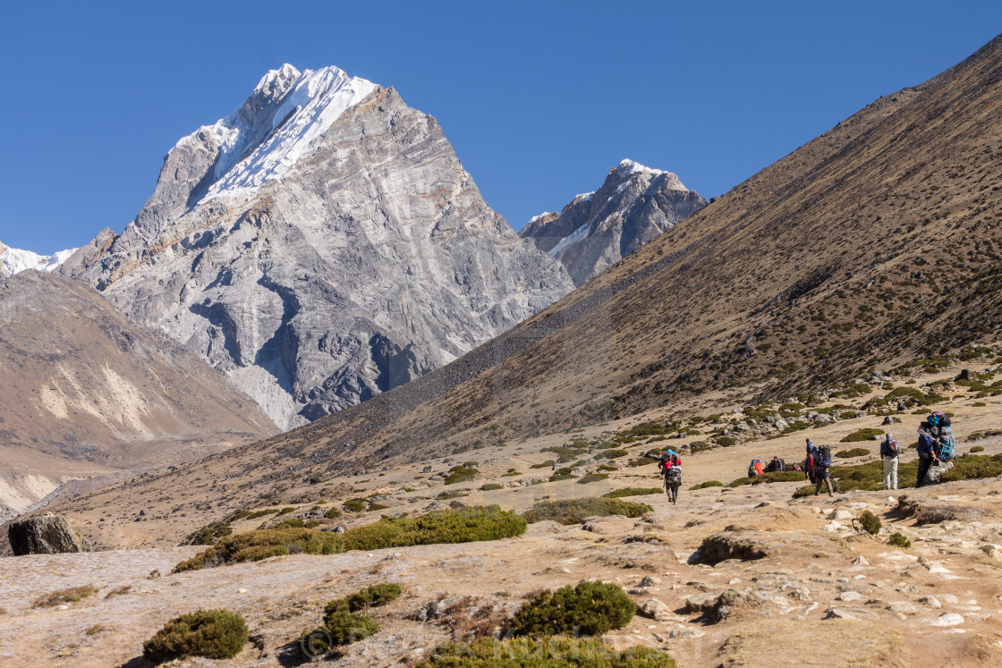 "Trekkers and porters heading towards Everest Base Camp on the trail above Dingboche" stock image