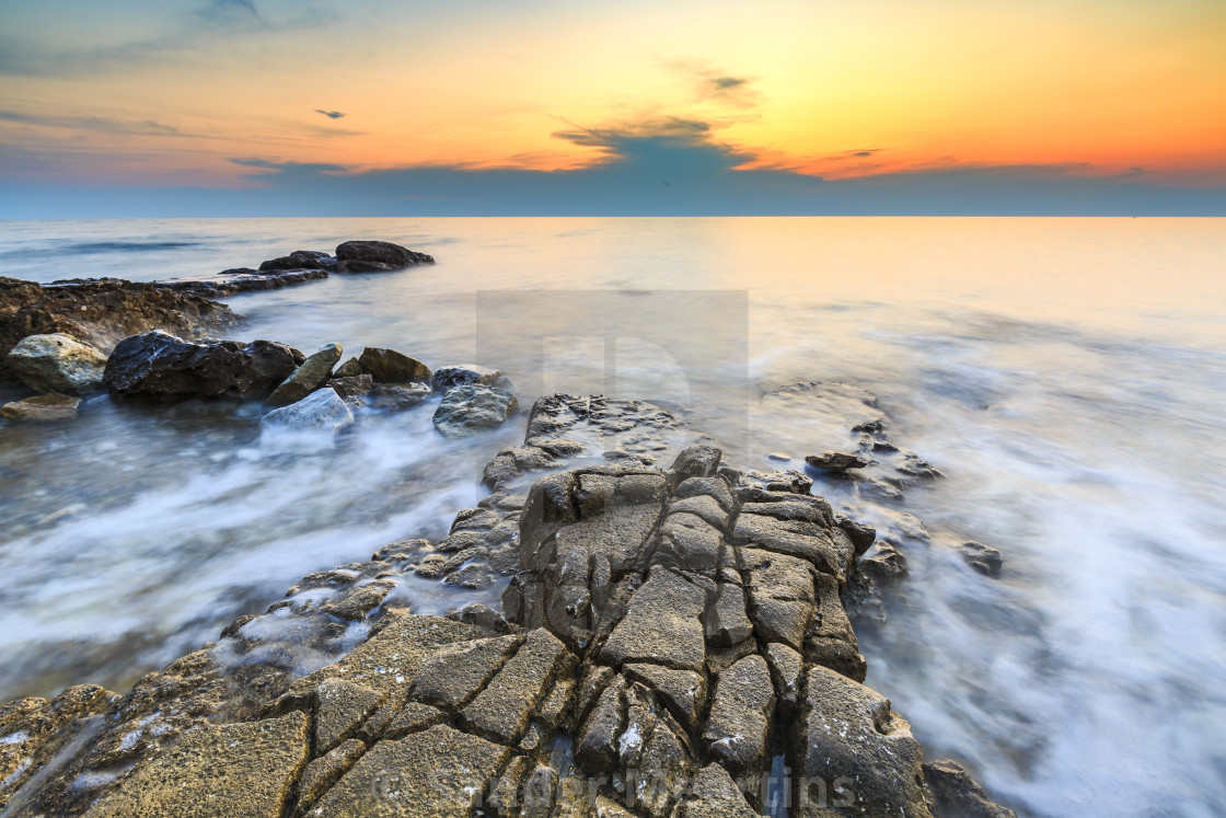 Enjoying The Colorful Sunset On A Beach With Rocks On The
