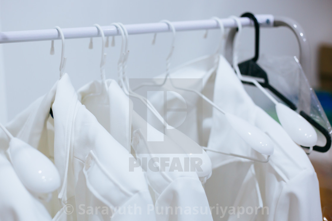White Doctor Gowns Being Hung On Hangers In Laundry Room In