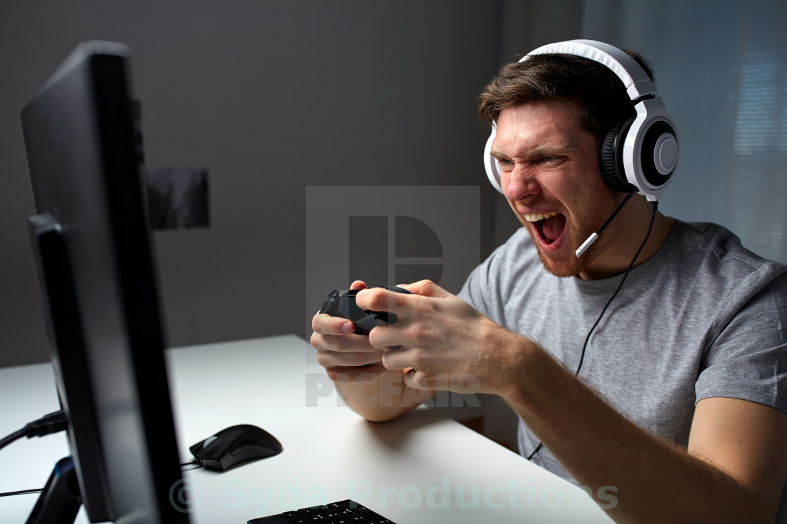 man in headset playing computer video game at home - License ...