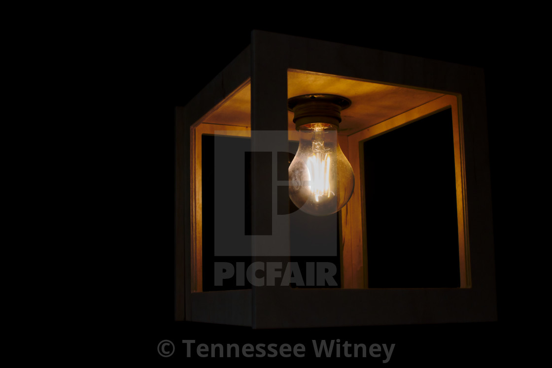 "Warm yellow glowing light bulb encased in a wooden box against a black..." by Tennessee Witney - £4.91 "Warm yellow glowing light bulb encased in a wooden box against a black..." stock image