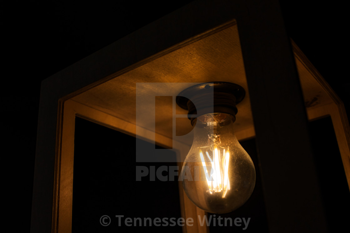 "Close-up of warm yellow glowing light bulb encased in a wooden box against a..." by Tennessee Witney - £4.91 "Close-up of warm yellow glowing light bulb encased in a wooden box against a..." stock image