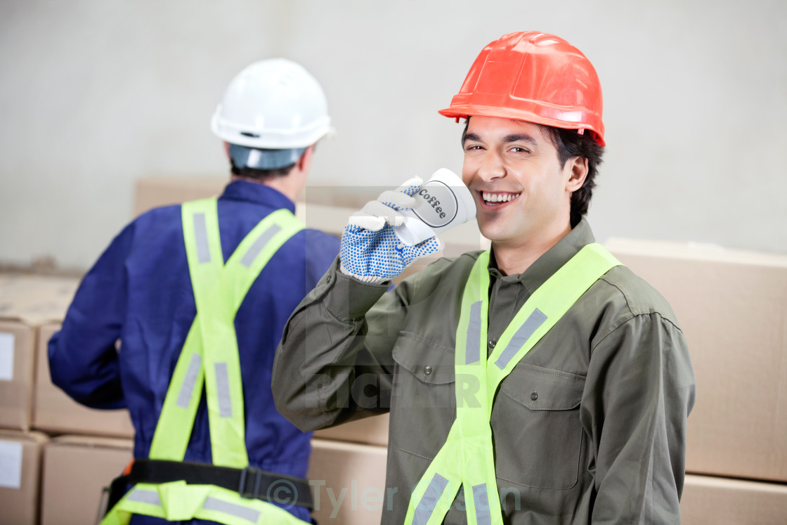 Foreman Drinking Coffee While Colleague Working At Warehouse