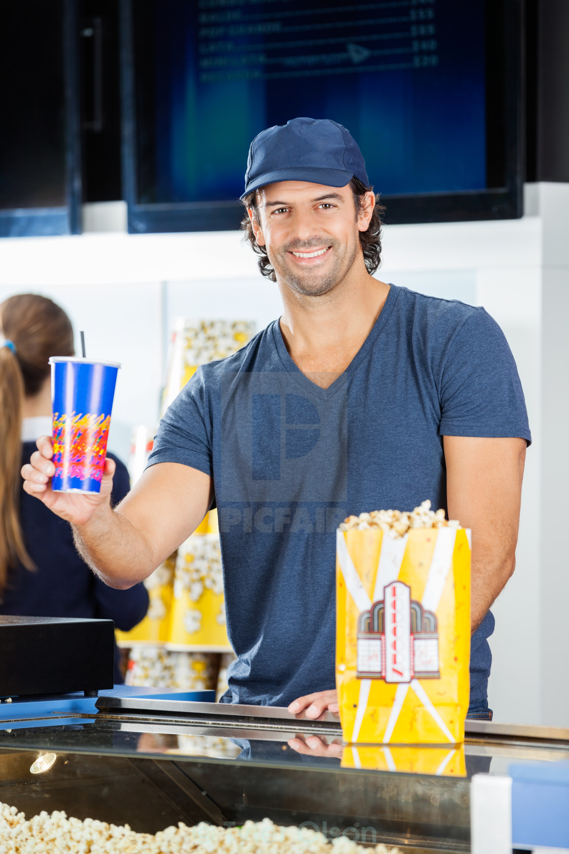 happy worker holding drink at cinema concession stand concession stand worker