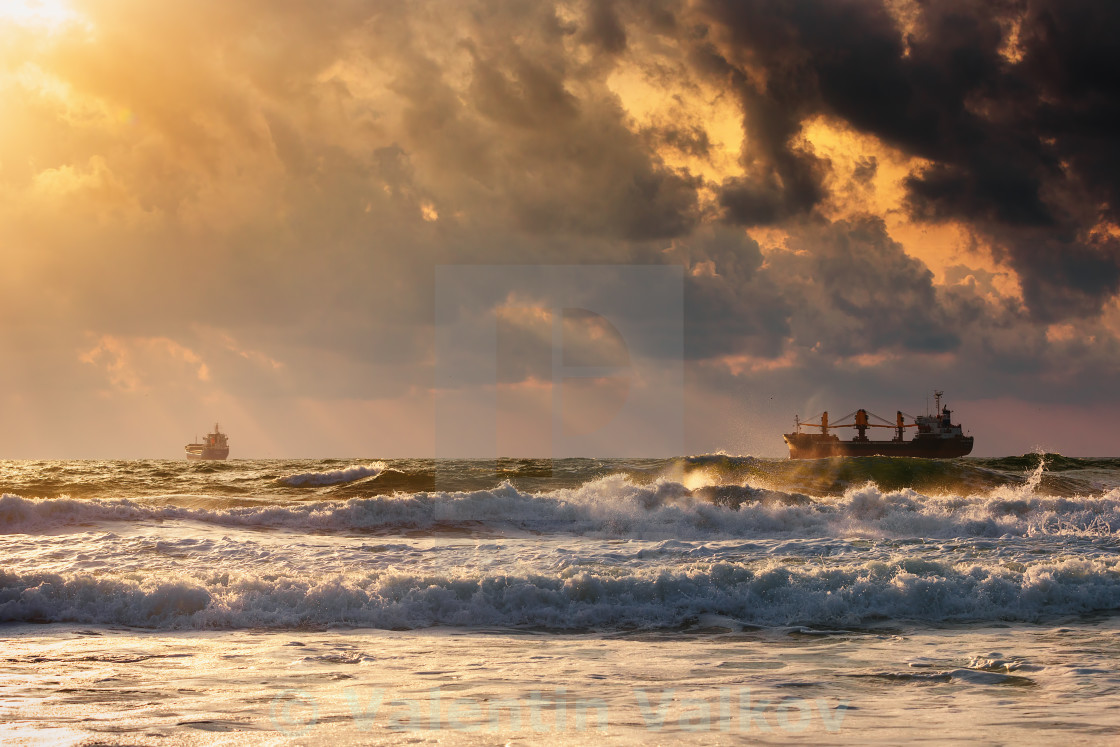 "Sun setting at the sea with sailing cargo ship, scenic view" stock image