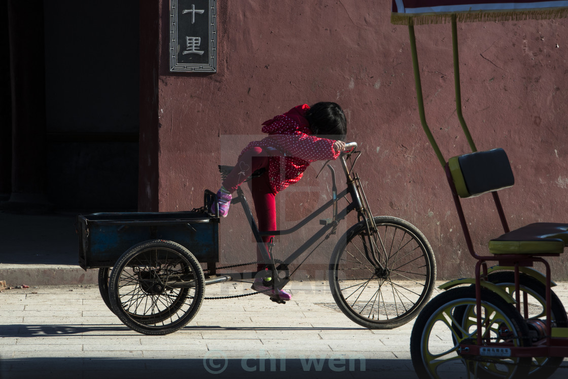 "A little girl playing with a tricycle, China" stock image