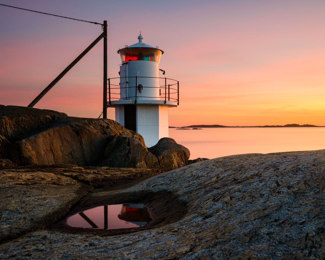 "Lighthouse at coast with dramatic sky at sunset" stock image