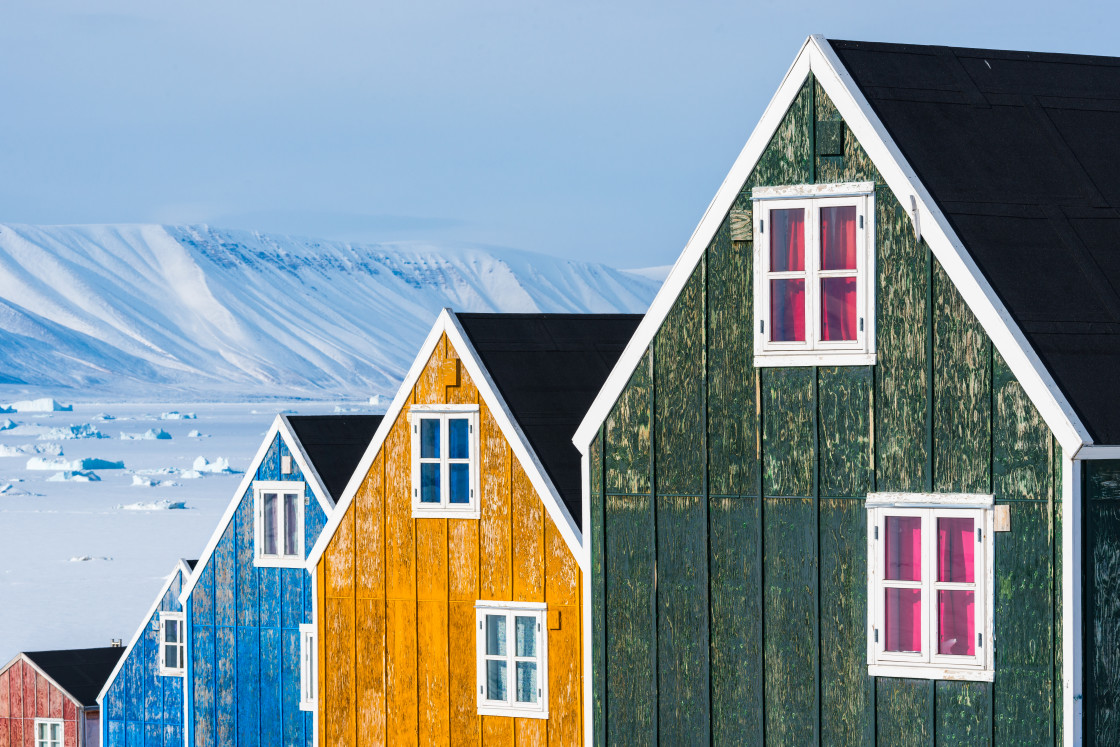 "Row of colourful wooden houses against a landscape of snow drifts" stock image