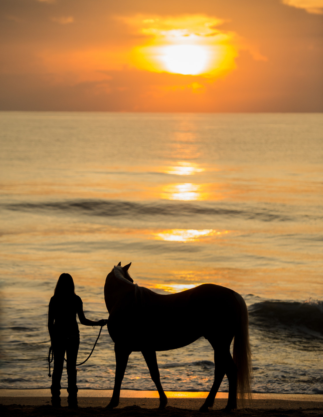 "Woman and horse at beach sunrise" stock image