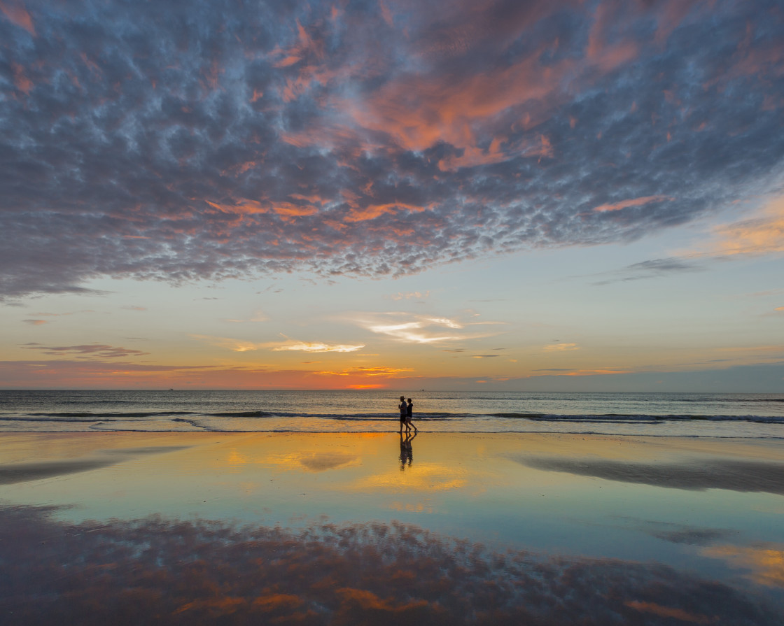 "Couple walking at sunrise on the beach" stock image