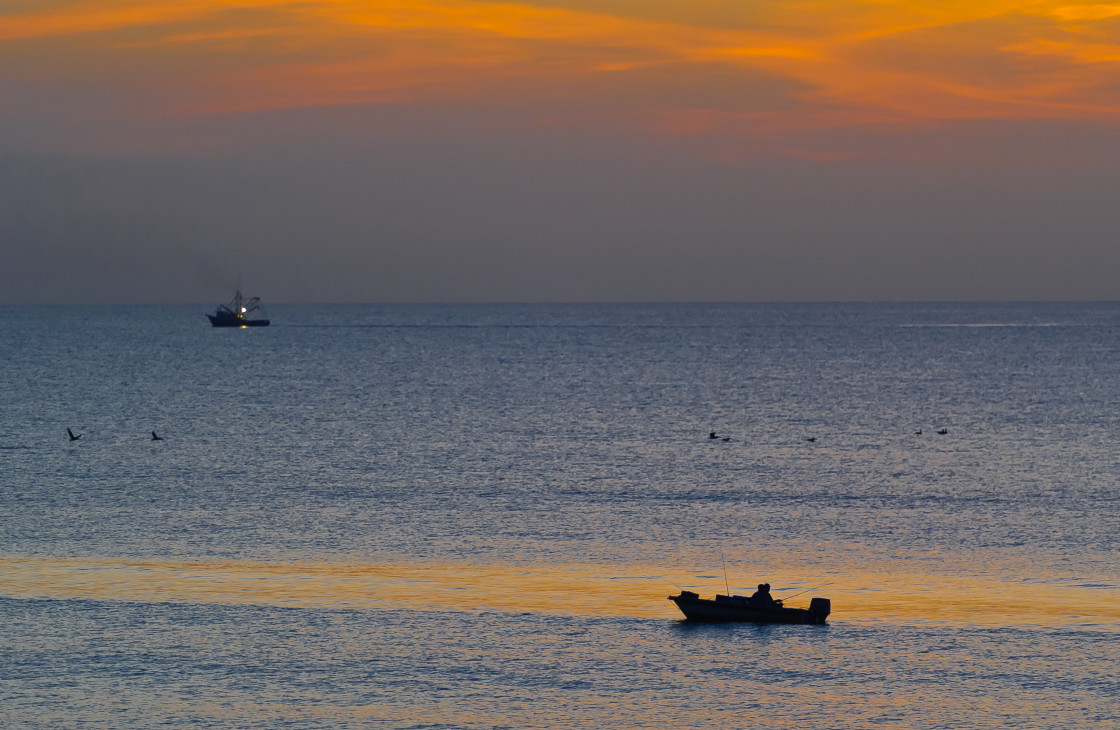 "Fishing boat at sunrise on the ocean." stock image