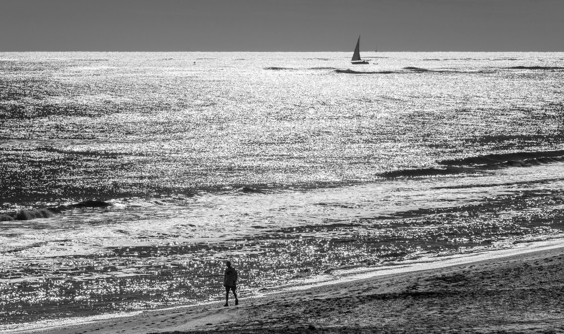 "Beach scene in black and white -sailboat and beach walker" stock image