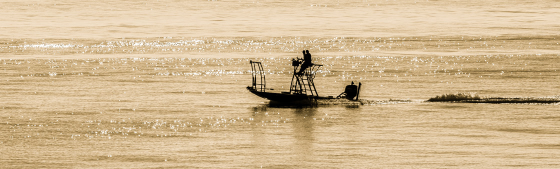 "Fishing boat at sunrise on the ocean." stock image