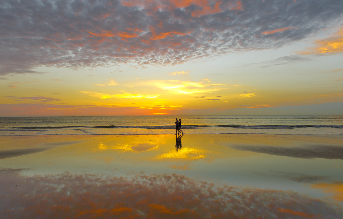 "Couple walking at sunrise on the beach" stock image