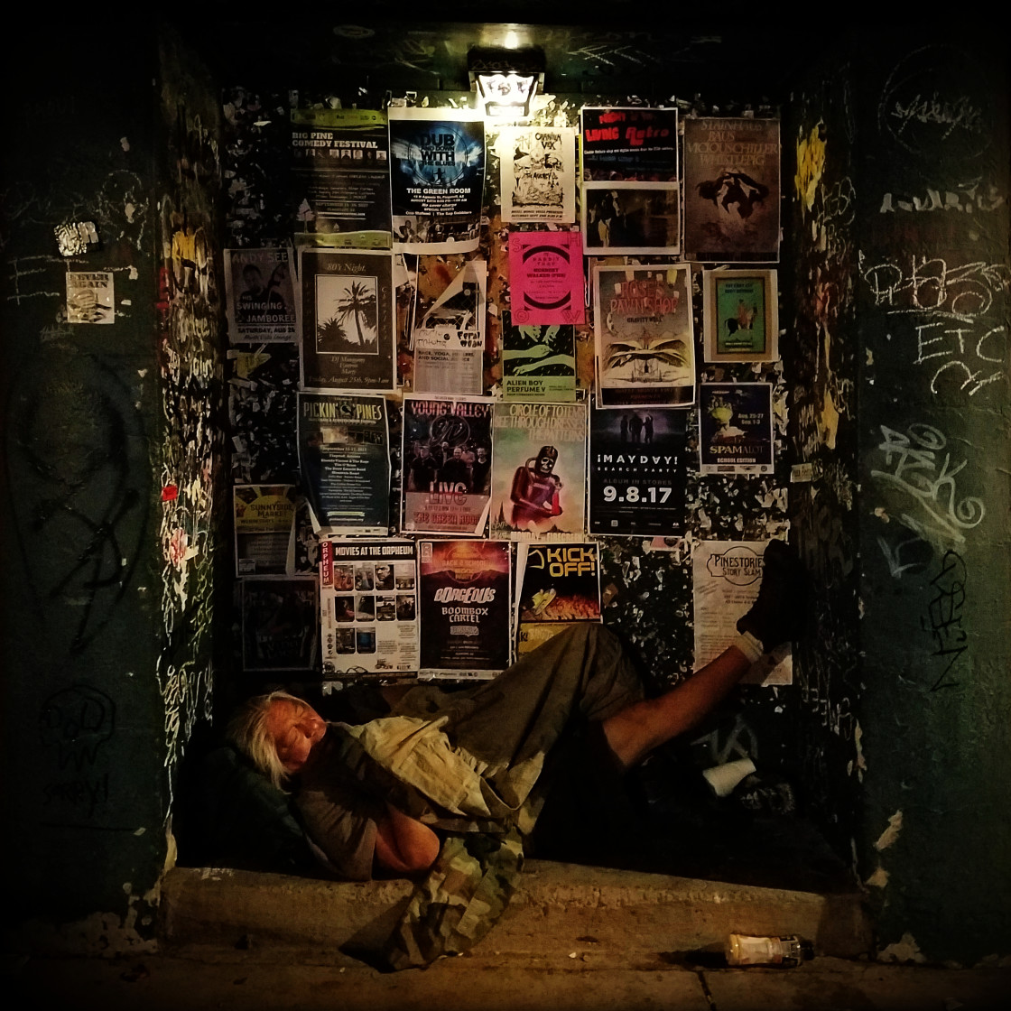 "A homeless man sleeps on the streets in an alcove amidst band flyers and graffiti." by Xomiele - £5.00 "A homeless man sleeps on the streets in an alcove amidst band flyers and graffiti." stock image