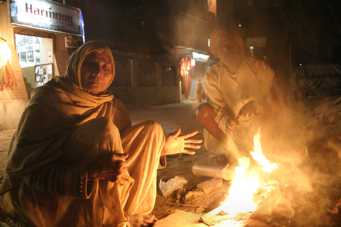 "Man and woman warming by fire, Varanasi, India" stock image