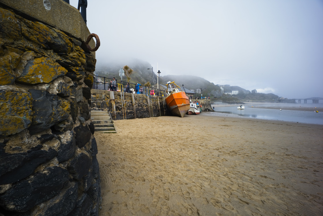 "Fishing boat leaning onto harbour wall" stock image