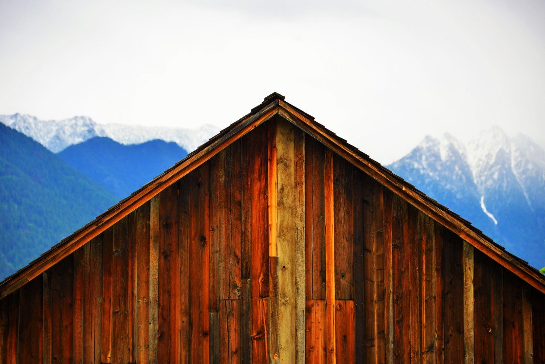 "Wooden barn building with Rocky Mountains in the background, Fort Steele, BC" stock image