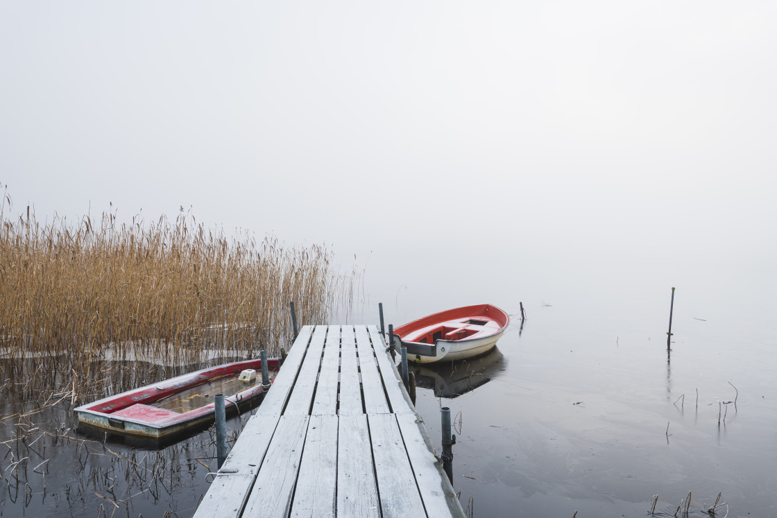 "Boats at frosty jetty in misty lake" stock image