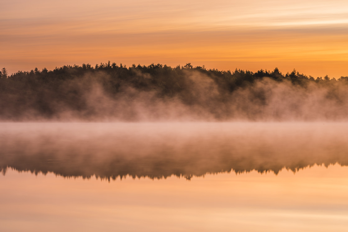 "Reflections on misty lake at sunrise" stock image